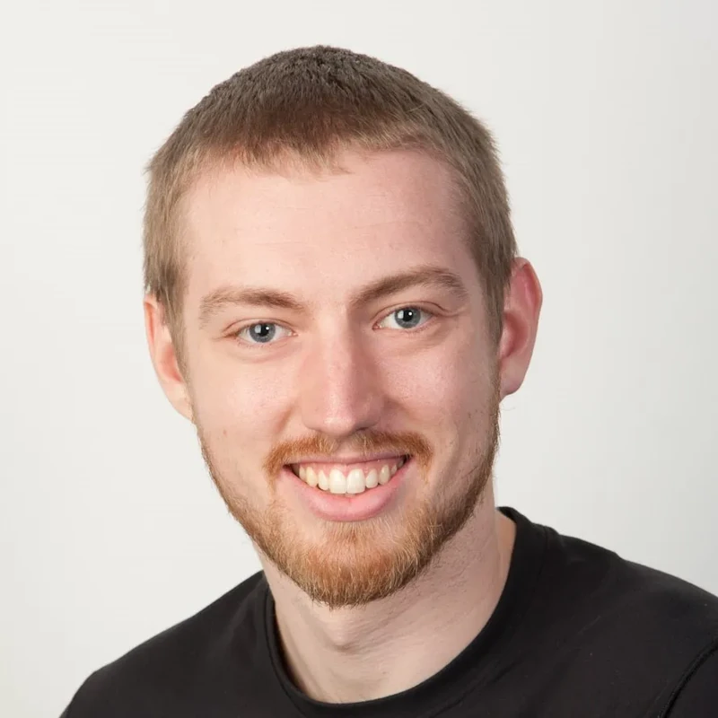 Tim Child, smiling, in a black t-shirt against a pale grey background